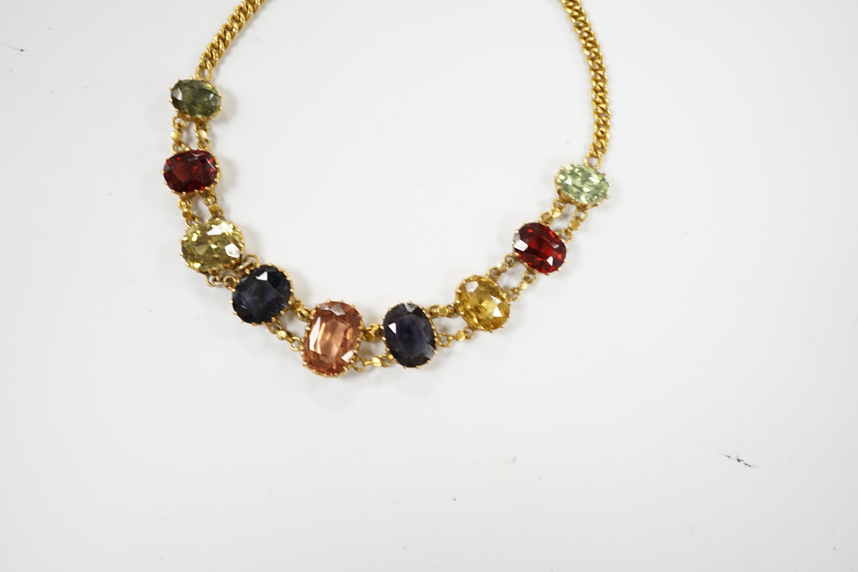 An early 20th century yellow metal and graduated multi-coloured oval cut zircon? set bracelet, 15.5cm, gross weight 7 grams.